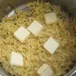Cooked noodles and butter for Sweet Noodle Kugel with Cornflakes