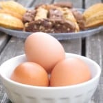 bowl of three raw eggs in front of baked goods