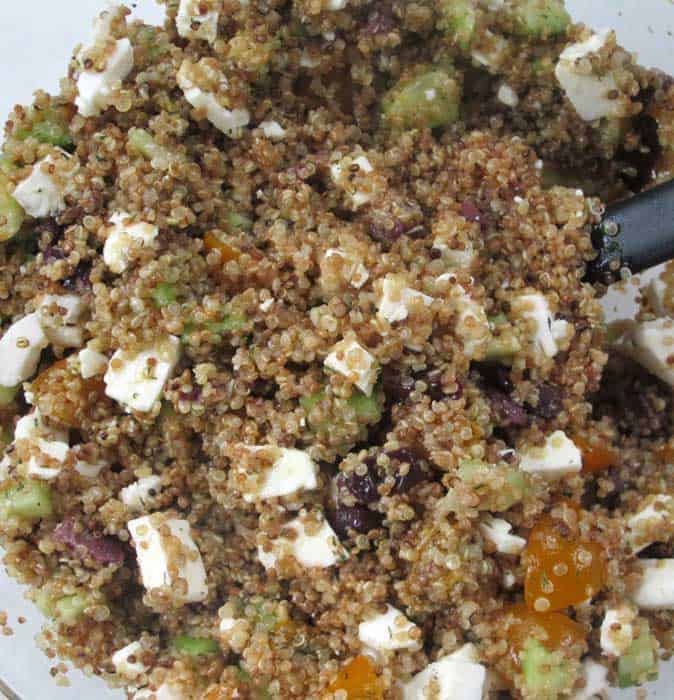 Adding in the dressing and feta cheese for quinoa and vegetable salad. | Mother Would Know