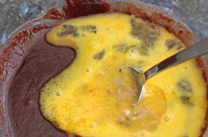 Adding eggs to the filling for a chocolate chess pie.