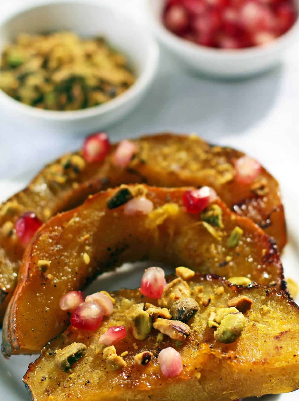 Roasted acorn squash slices topped with pomegranate seeds and roasted, chopped pistachios | Mother Would Know