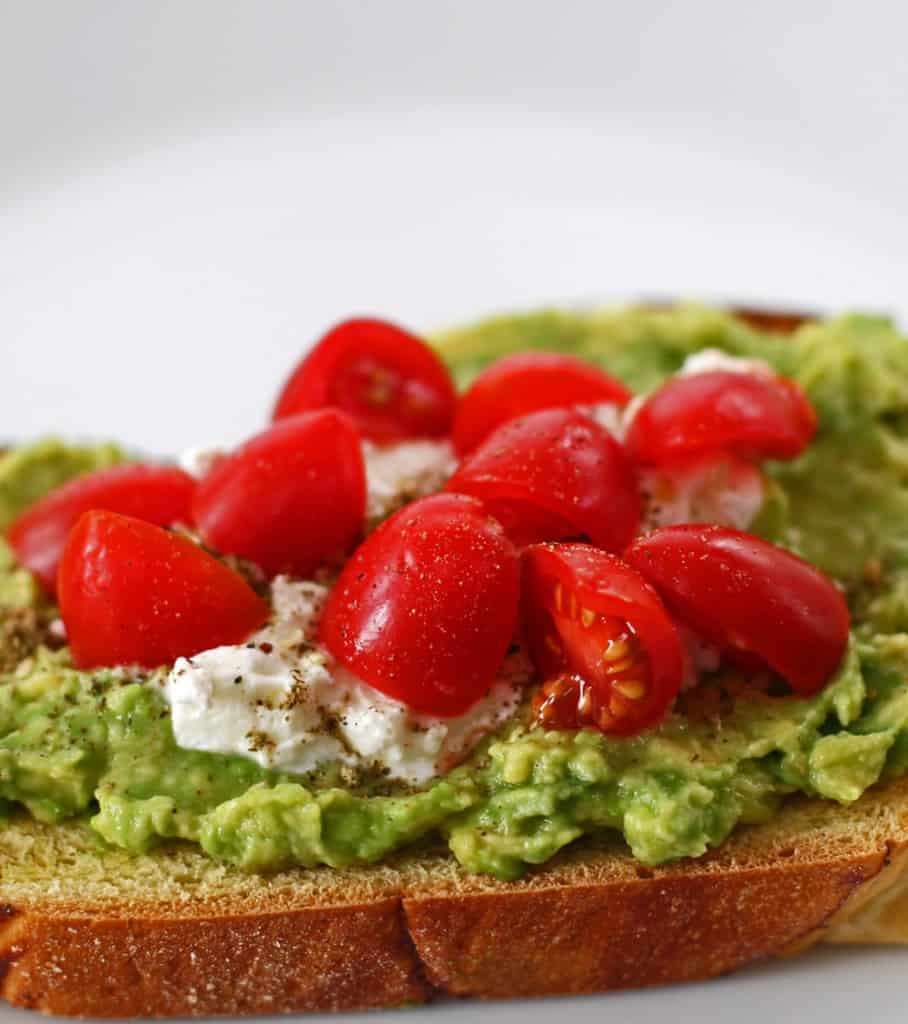 a piece of avocado toast with za'atar and feta topped with tomatoes