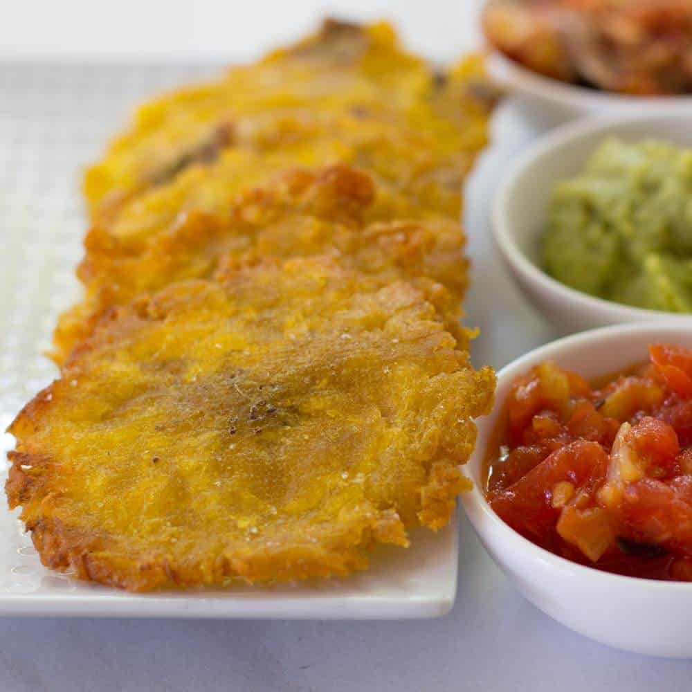Patacones or fried green plantains done with toppings on the side.