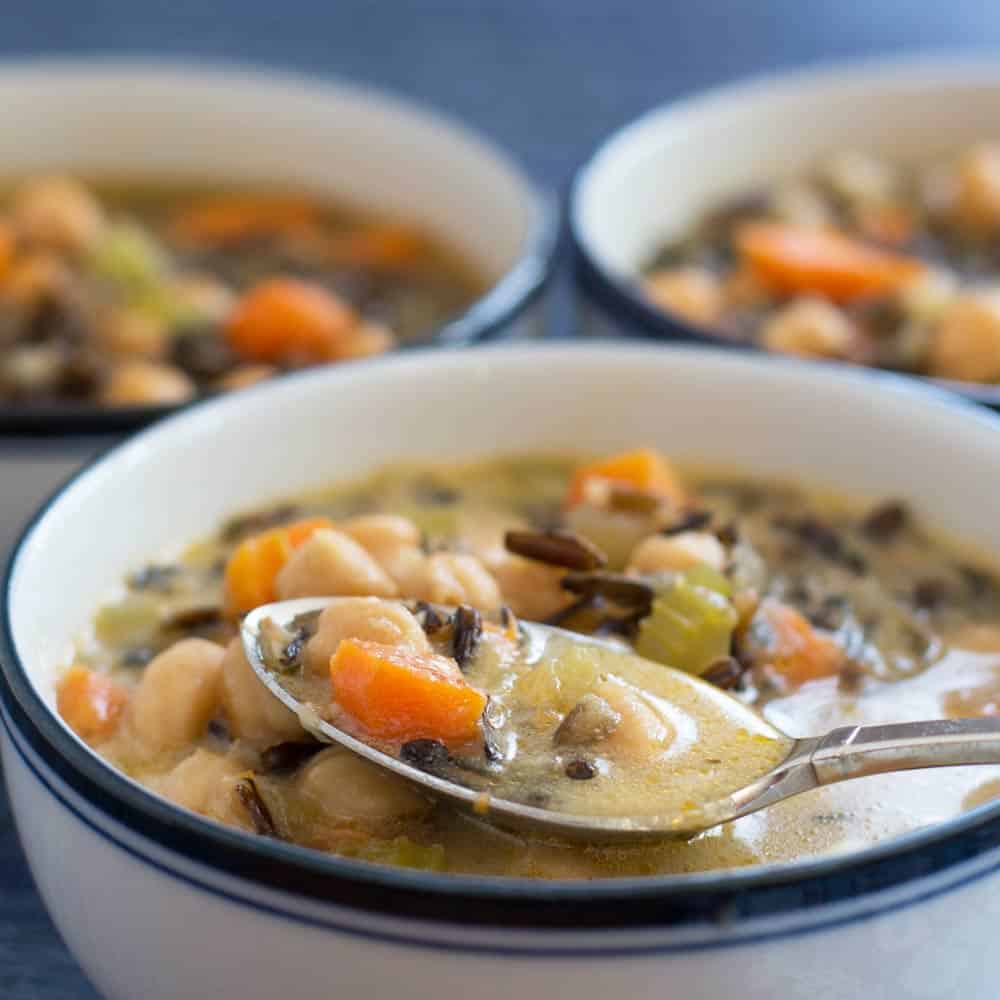 Vegan Creamy Wild Rice Soup in 3 bowls, with spoon in front bowl