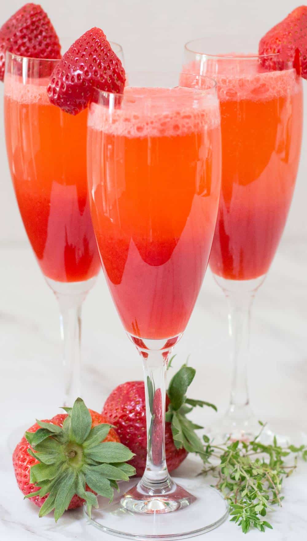 3 champagne glasses filled with strawberry bellini 