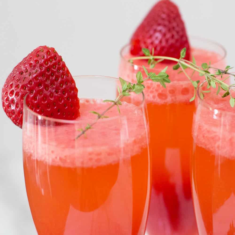 closeup of starwberry bellini with strawberry and thyme garnish