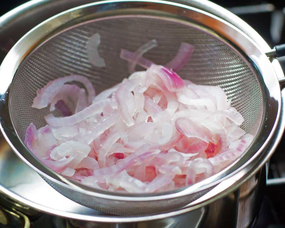 Draining the red onion slices after blanching