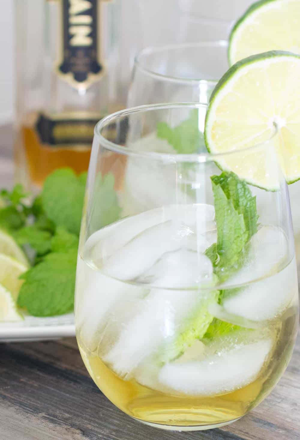 Hugo cocktail in a glass with elderflower liqueur bottle behind