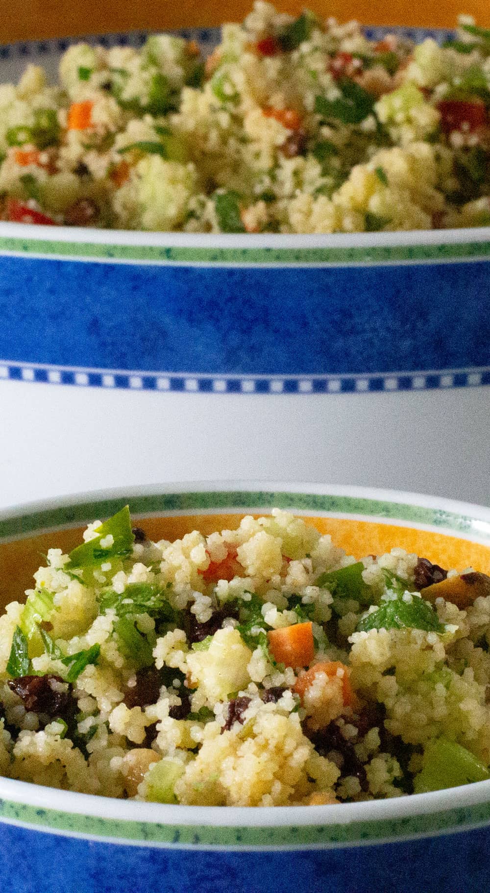 A small bowl of minty couscous salad in front of a larger bowl