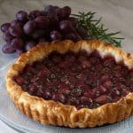 Roasted red grape and rosemary tart with bunch of grapes and fresh rosemary in background