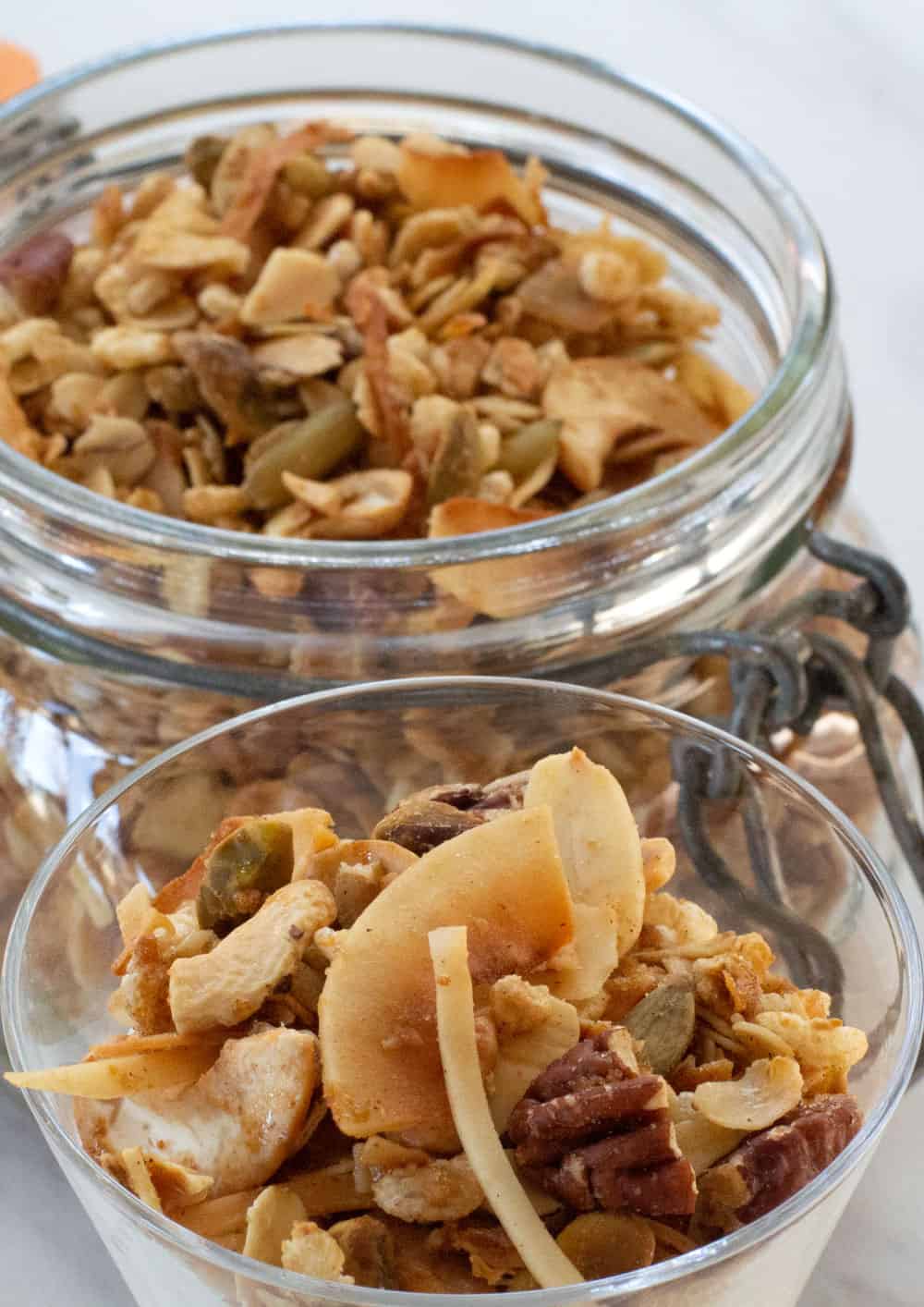 cup of crispy granola with a jar of granola behind