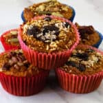pumpkin yogurt muffins stacked with one topped with chips and unsweetened coconut on top
