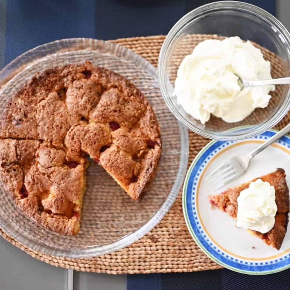 Summer Fruit Cornmeal Cake overhead with piece cut out on plate and whipped cream 