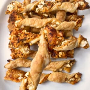 closeup of Greek-style puff pastry breadstick in front with many on plate below