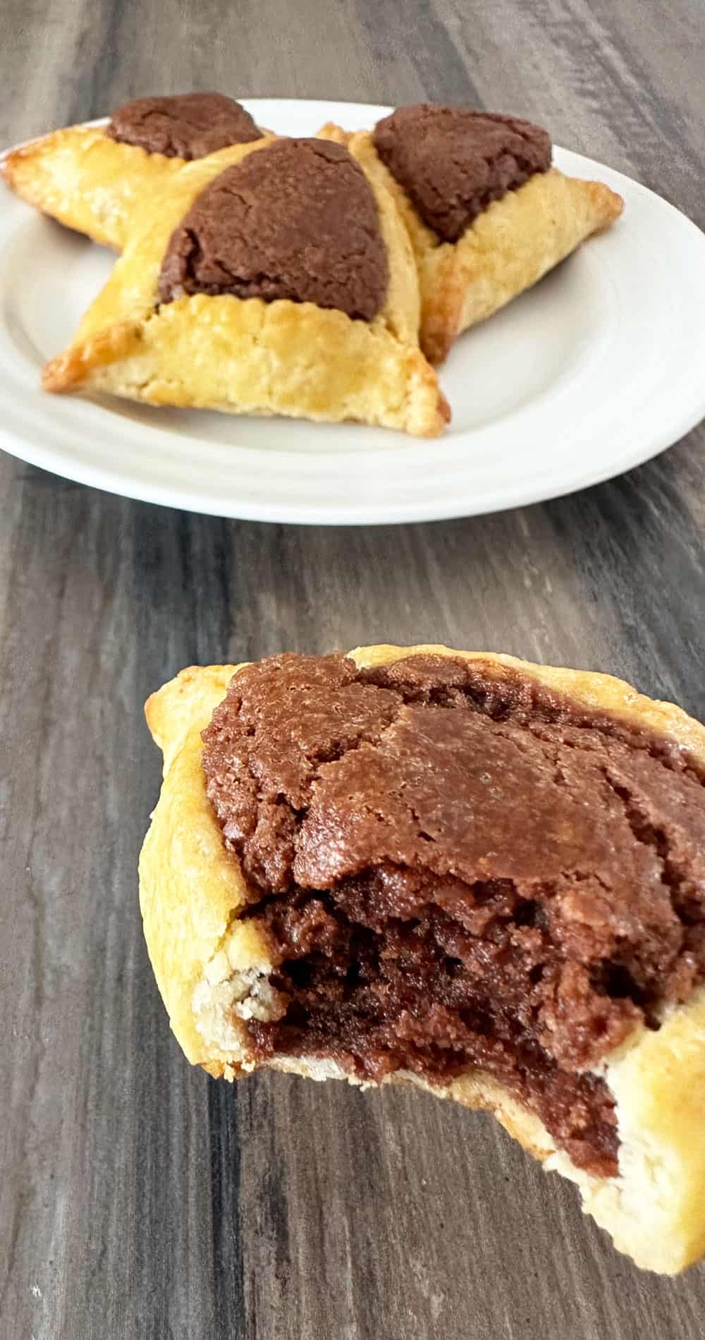 Piece of Nutella Hamantaschen in front of a plate of hamantaschen