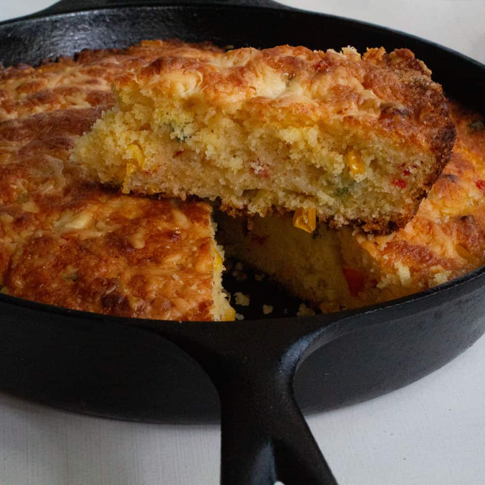 piece of loaded cornbread baked on top of pan of cornbread after baking