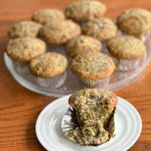 lemon poppy seed muffin open in front of plate of baked muffins