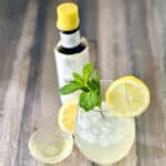 Sparkling lemon mint mocktail with isimple syrup and bitters next to the glass.