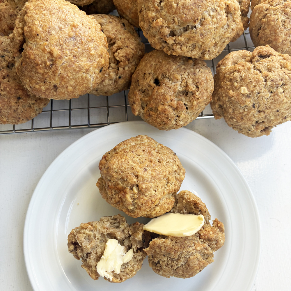 matzo rolls on a plate with wire rack of stacked matzo rolls behind